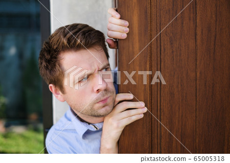 Young caucasian man with agoraphobia spying and 65005318