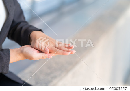woman cleansing hands by sanitizer alcohol gel in public 65005357