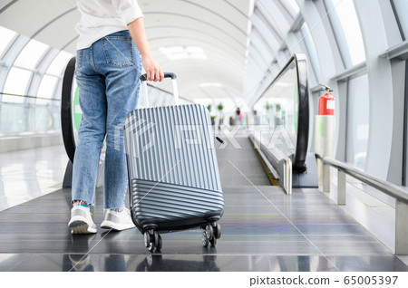 Woman carrying suitcase in airport terminal 65005397