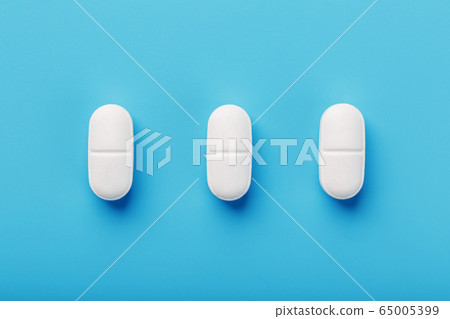 Medicinal tablets in a row on a blue background, 65005399