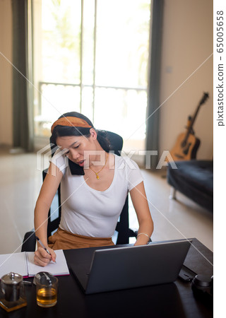 Busy woman on a phone meeting while working from Busy woman on a phone meeting while working from 65005658