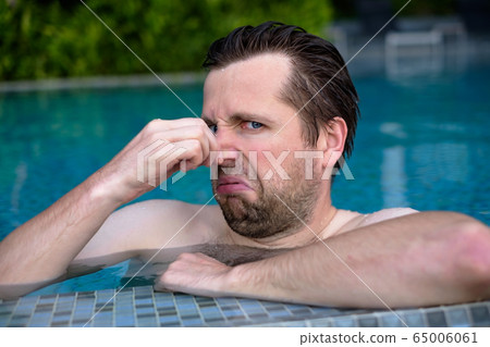 young man with disgust on his face pinches nose, 65006061