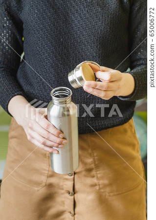 Woman open reusable stainless steel water bottle 65006772