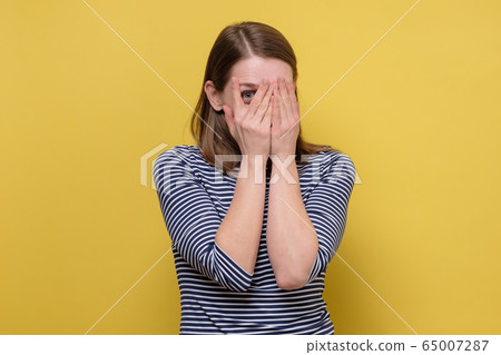 curious woman looking through fingers, peeking 65007287