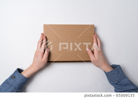 Cardboard box in children's hands on white 65009135