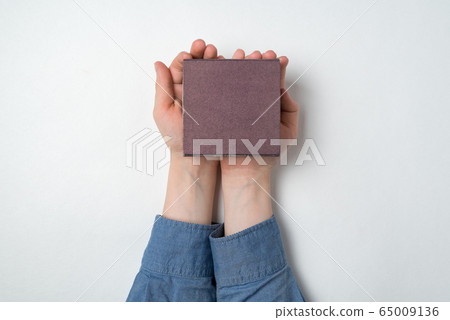 Children's hands holding small gift box on white 65009136