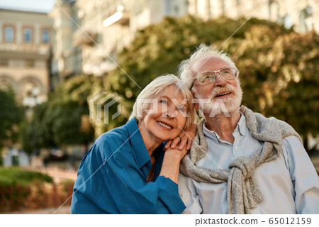 Endless love. Portrait of beautiful senior woman leaning at shoulder of her husband and smiling while spending time together outdoors on a sunny day Endless love. Portrait of beautiful senior woman leaning at shoulder of her husband and smiling while spending time together outdoors on a sunny day 65012159