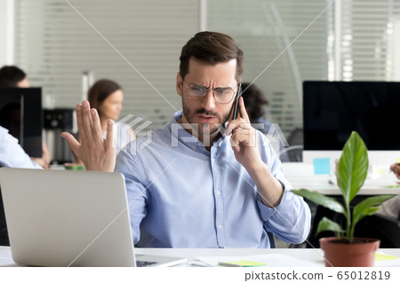 Angry businessman caller talking on phone disputing over compute 65012819