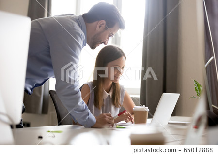Smiling intern listening to friendly mentor explaining online wo Smiling intern listening to friendly mentor explaining online wo 65012888