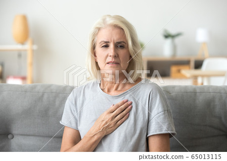 Upset stressed mature older woman feeling heartache touching che 65013115