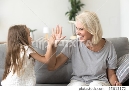 Little granddaughter and happy grandmother giving high five play 65013172