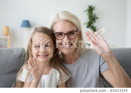 Portrait of grandmother and kid waving hands looking at camera 65013245