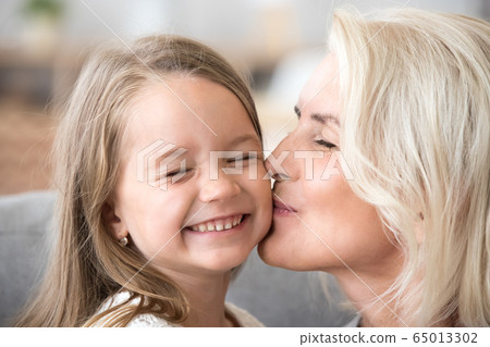 Loving old grandmother kissing cute preschool granddaughter on c Loving old grandmother kissing cute preschool granddaughter on c 65013302