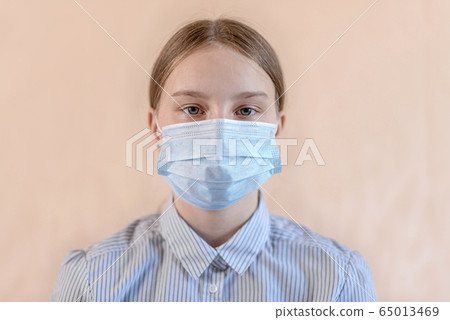 Close-up portrait beautiful teenager 12-15 years old, covers his face wearing medical blue mask, anti-coronavirus COVID-19 pandemic infectious disease outbreak protection, healthcare concept 65013469