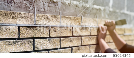 Wall cladding. Decorative bricks with rocky relief surface. Wide-angle background with copy space Wall cladding. Decorative bricks with rocky relief surface. Wide-angle background with copy space 65014345