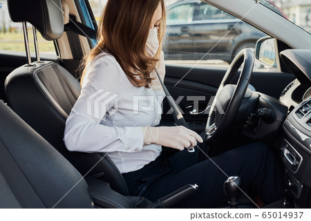 Woman in protective mask and gloves fastens seat Woman in protective mask and gloves fastens seat 65014937