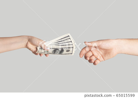 Closeup of girl offering money to young guy against light background Closeup of girl offering money to young guy against light background 65015599