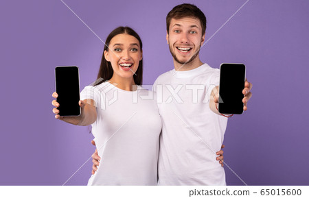 Happy couple showing blank cellphone screen to camera Happy couple showing blank cellphone screen to camera 65015600