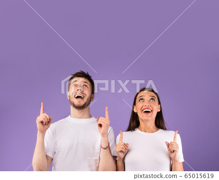 Smiling couple pointing fingers up at free space Smiling couple pointing fingers up at free space 65015619
