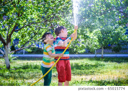 Brothers having fun splash each other with water Brothers having fun splash each other with water 65015774