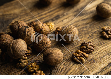 Walnut scattered on the wooden vintage table. Walnuts is a healthy vegetarian protein nutritious food. Walnut on rustic old wood. 65016112