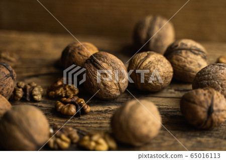 Walnut scattered on the wooden vintage table. Walnuts is a healthy vegetarian protein nutritious food. Walnut on rustic old wood. 65016113