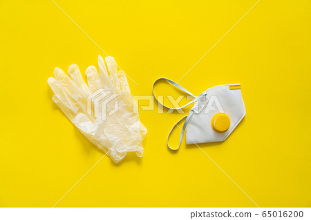 Respirator ffp and rubber gloves lie on a yellow background. Anti-virus protection kit against covid-19. Coronavirus pandemic 2019. Respirator ffp and rubber gloves lie on a yellow background. Anti-virus protection kit against covid-19. Coronavirus pandemic 2019. 65016200