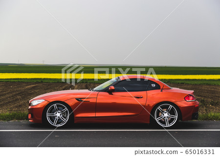 Orange color business class car speed motion in the highlands, foggy weather Orange color business class car speed motion in the highlands, foggy weather 65016331