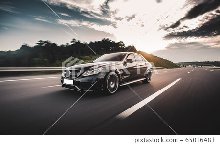 Black sedan travelling in the highlands in a sunny day Black sedan travelling in the highlands in a sunny day 65016481