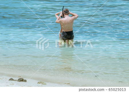 A gentleman helped wear glasses for his lover before snorkelling to see the beautiful coral in the sea. 65025013