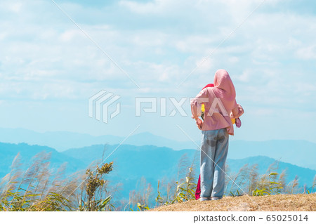 Back view of Muslim women wearing a Muslim dress and hijab enjoy on the highest point and the beautiful view landscape in morning at Elephant Hills  View Point are located in Thong Pha Phum Kanchanabu 65025014