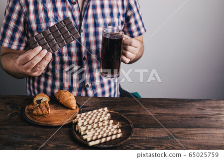 Overweight man with big amount of sugary food 65025759
