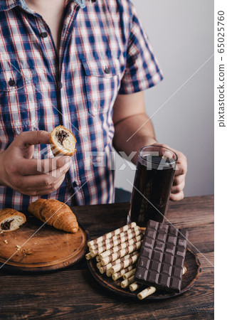 Overweight man with big amount of sugary food 65025760
