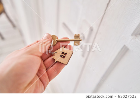 Modern light lobby interior. Men hand holding key with house keychain. Real estate, moving home or renting property. Mortgage concept. Modern light lobby interior. Men hand holding key with house keychain. Real estate, moving home or renting property. Mortgage concept. 65027522