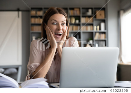 Excited surprised woman looking at laptop screen, reading news Excited surprised woman looking at laptop screen, reading news 65028396
