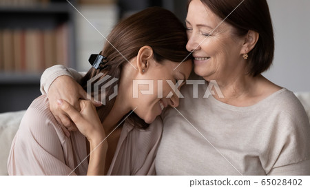 Smiling mature mother hugging adult daughter, enjoying tender moment 65028402