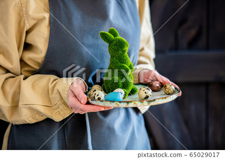 Female in apron holds green decorative Easter Female in apron holds green decorative Easter 65029017