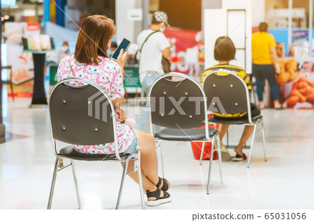 Back view of people order food and wait to take home inside of department store closed due to the coronavirus (Covid-19), Restaurants set chairs for social distancing to waiting for the food. Back view of people order food and wait to take home inside of department store closed due to the coronavirus (Covid-19), Restaurants set chairs for social distancing to waiting for the food. 65031056
