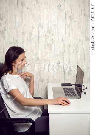 girl in isolation quarantine is sitting at a white table at a laptop girl in isolation quarantine is sitting at a white table at a laptop 65031107