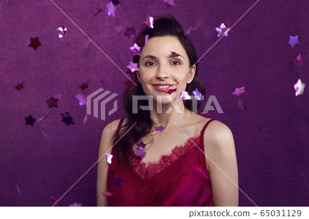 woman in a red top stands against a purple wall woman in a red top stands against a purple wall 65031129