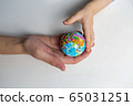 baby and hand of adult man holding a small globe during the epidemic 65031251