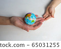 baby and hand of adult man holding a small globe during the epidemic 65031255