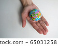 a man's adult hand holds a small globe in the palm 65031258