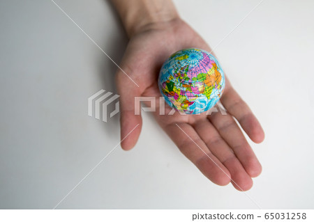 a man's adult hand holds a small globe in the palm a man's adult hand holds a small globe in the palm 65031258