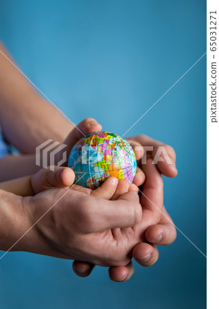 baby and hand of adult man holding a small globe during the epidemic 65031271