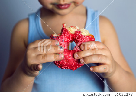 boy is holding two colored doughnuts blue and red in front boy is holding two colored doughnuts blue and red in front 65031278