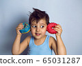 boy is holding two colored doughnuts blue and red in front 65031287