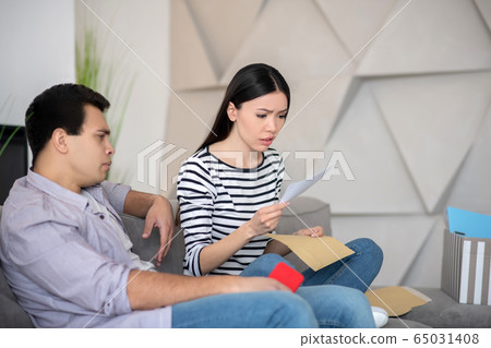 Woman reading letter near man with smartphone. 65031408