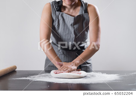 Hand-stretching dough by female hands at home. 65032204