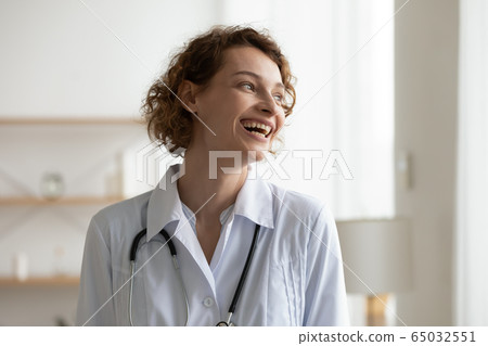 Cheerful successful young female doctor looking away and laughing 65032551